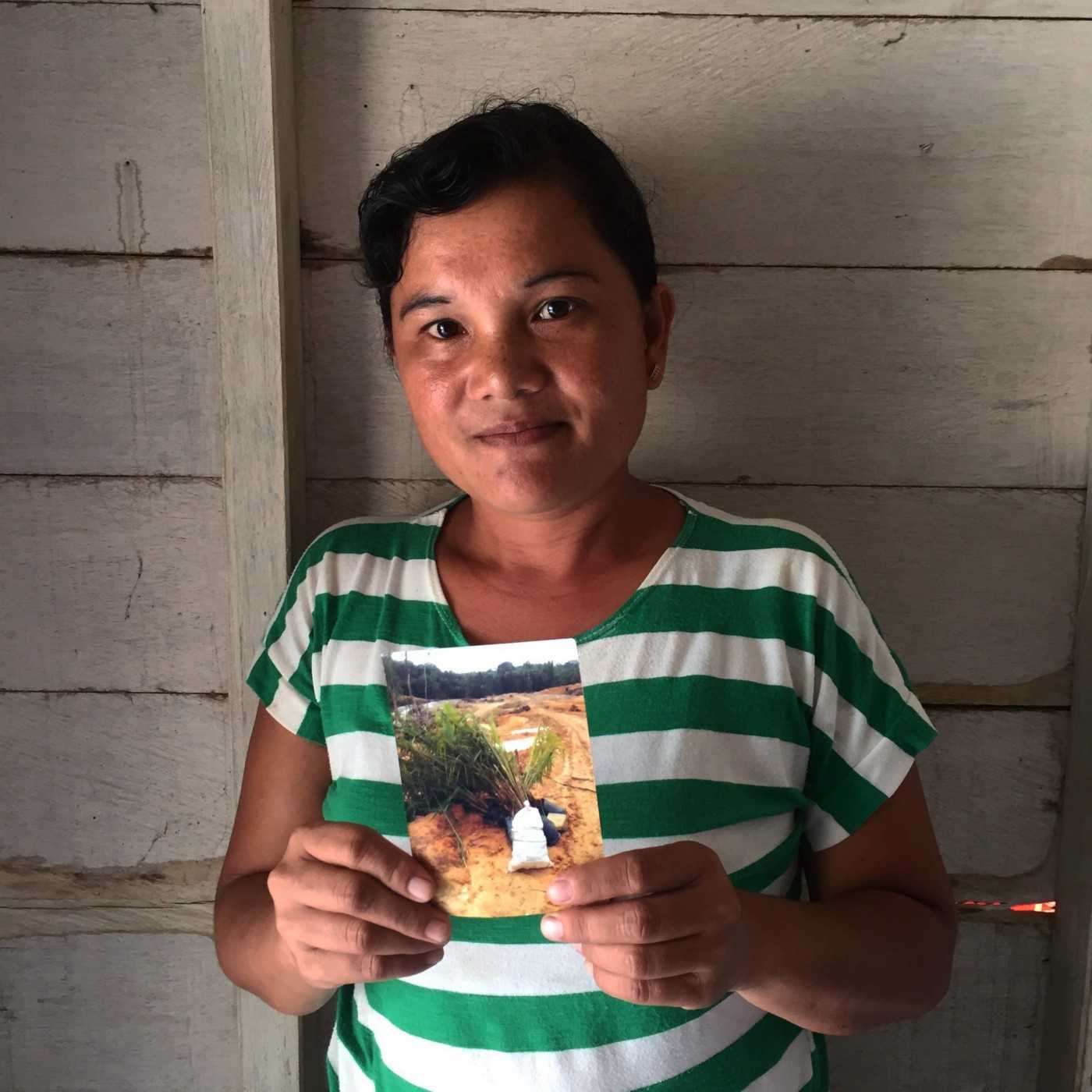 Erma Kusmini with a photo of the land once occupied by her family’s forest farm, now destroyed