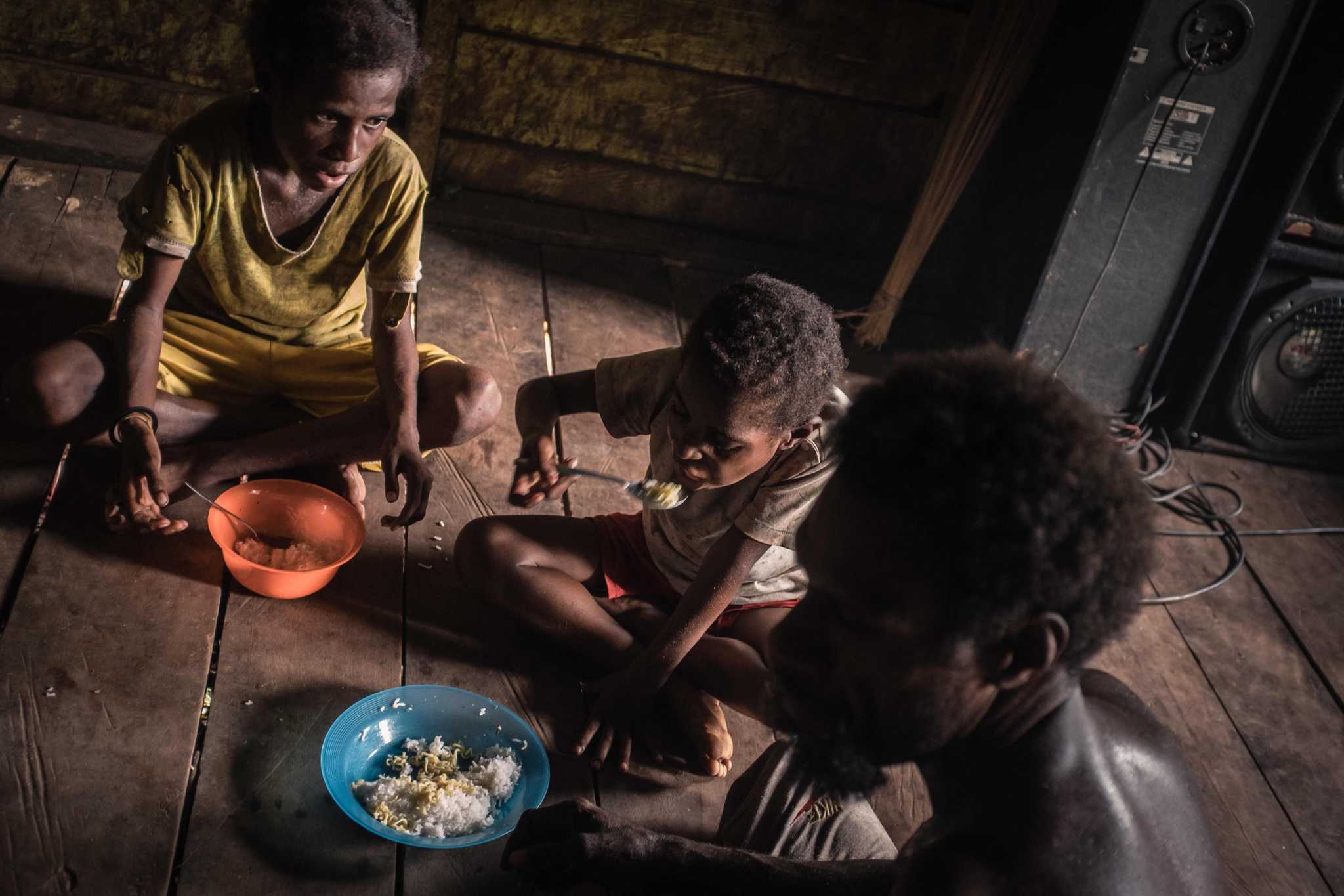 Photo of a family eating a meal in the village of Zanegi, Merauke district.
