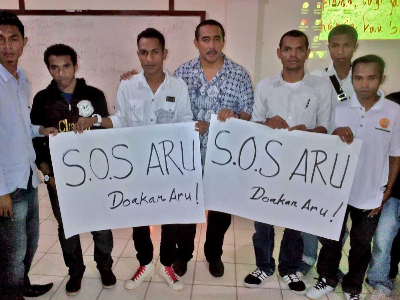 Activists holding 'SOS Aru' signs.